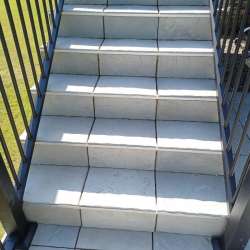 Locking in DekTek's concrete deck tiles installed on stairs with aluminum edge trim